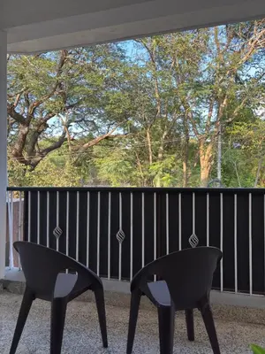 two chairs on a balcony with a large window at Arranyaa retreatt- Girrafe's gallery in Mysore