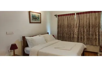 a bedroom with a white bed with a window at Brooklyn Villa in Ooty
