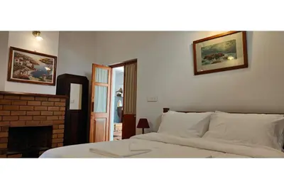 a bedroom with a white bed and a fireplace at Brooklyn Villa in Ooty