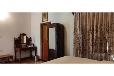 a bedroom with a bed and a dresser and a mirror at Brooklyn Villa in Ooty