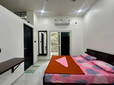 a bedroom with a bed with pink sheets and a table at Nana's Residency, Cochin in Alwaye