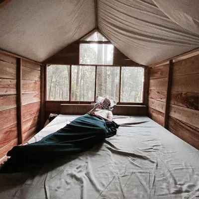 a person laying on a bed in a tent at Wildvibes India in Meppādi
