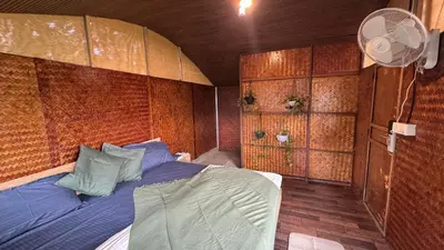a bedroom with a bed in a room with a fan at Wildvibes India in Meppādi