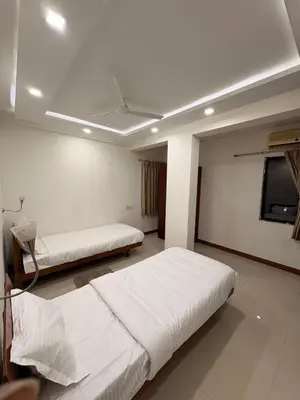 a bedroom with two beds and a tv on the wall at Isha suites in Mysore