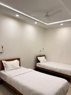 two beds in a room with white walls at Isha suites in Mysore