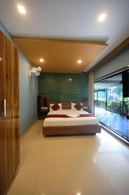 a bedroom with a large bed and a large window at Snow Drops Resort in Vythiri
