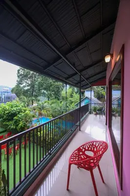 a red chair on the balcony of a house at Snow Drops Resort in Vythiri