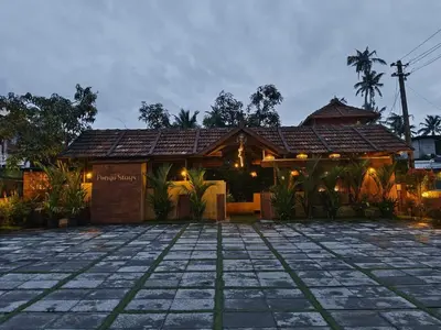 a house with a tile roof and a stone patio at Ponyo Stays in Cochin