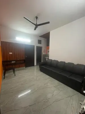 a living room with a black couch and a ceiling fan at Mount holidays in Meppādi