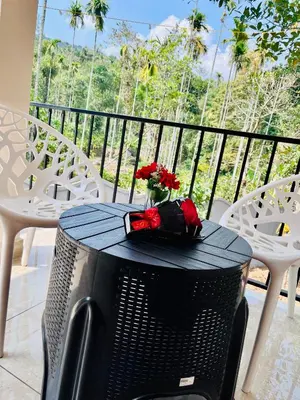 a table with a television and flowers on a balcony at Ronz Vista Mount Villa in Padinjarathara