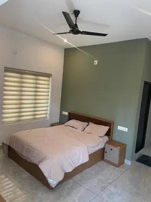 a bedroom with a bed and a ceiling fan at Vijaya Home Stay in Batheri