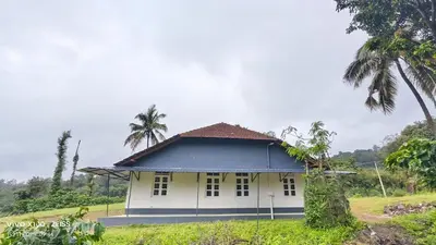 a white house with a blue roof and palm trees at Mathew's Haven, Wayanad - By Arattukulam Hospitality in Thirunelli