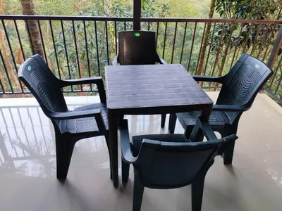 a wooden table and two chairs on a balcony at Vythiri Silent Leaf in Wayanad
