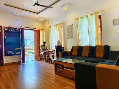 a living room with a couch and a person sitting at a table at z in wayanad in Kalpetta