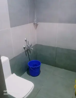 a bathroom with a toilet and a blue bucket at Nalukettu Veedu in Thottada