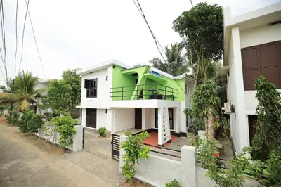 a green and white house with trees in front of it at Ashiyana Homes in Nedumbassery