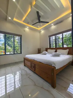 a bedroom with a large bed with a ceiling at Surya Homestay in Marayoor