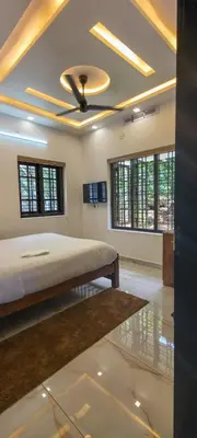 a bedroom with a bed and a ceiling fan at Surya Homestay in Marayoor