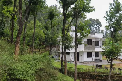 a white house in the middle of a forest at Surya Homestay in Marayoor