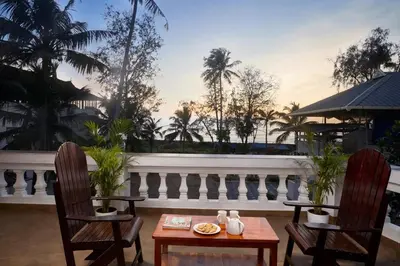 a patio with two chairs and a table and a balcony at Akanta Cherai Beach Resort in Cochin