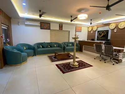 a living room with blue couches and a desk at PANCHAVADY RESIDENCy in Kodungallūr