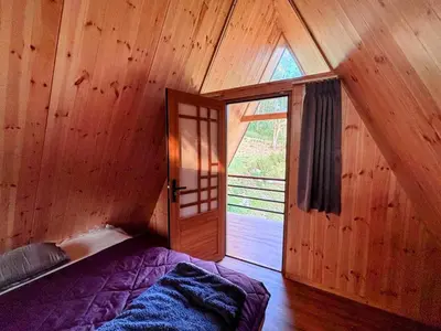 a bedroom with a bed in a wooden room with a door at AURA Resort kookal kodaikanal in Kūkkāl