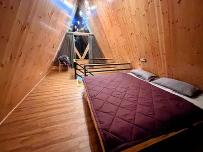 a bed in a wooden room with a window at AURA Resort kookal kodaikanal in Kūkkāl