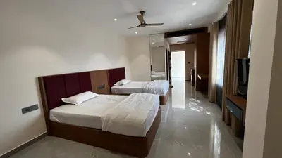 two beds in a hotel room with a tv and a room at Cloud Nine Hotel - Kuthuparamba in Kuthuparamba