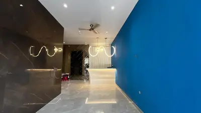 a hallway with a blue wall and chandeliers at Cloud Nine Hotel - Kuthuparamba in Kuthuparamba
