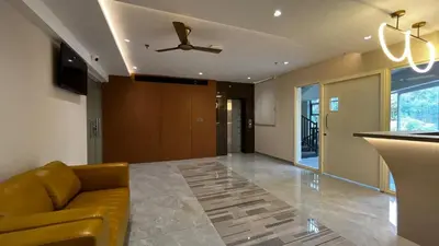 a living room with a couch and a ceiling fan at Cloud Nine Hotel - Kuthuparamba in Kuthuparamba