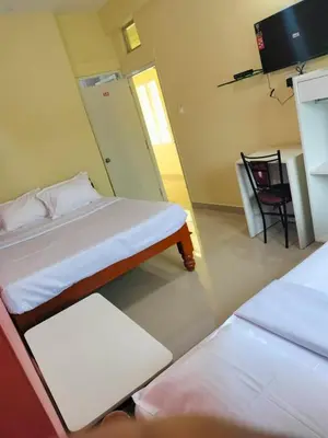 a room with two beds and a table and a chair at ISIRI Rooms in Mysore