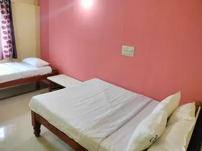 a room with two beds and a red wall at ISIRI Rooms in Mysore