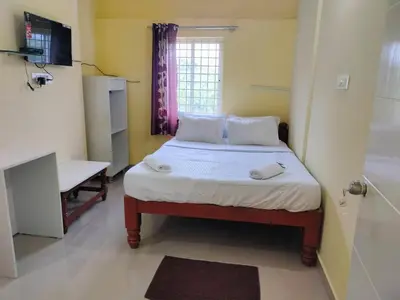 a small bedroom with a bed and a bathroom at ISIRI Rooms in Mysore