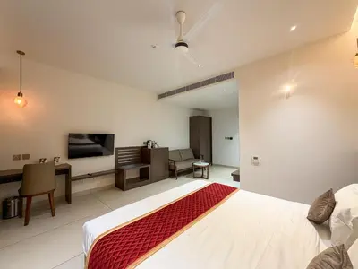 a bedroom with a bed and a desk and a tv at Hotel Grand Residency in Mannārakkāt