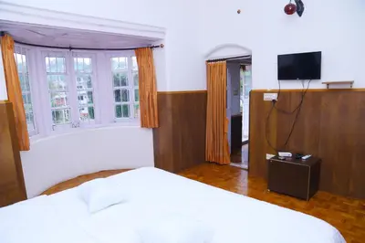 a bedroom with a bed and a tv and windows at Celestial Resorts in Kotagiri