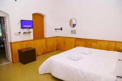 a bedroom with a white bed and a tv at Celestial Resorts in Kotagiri