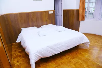a bedroom with a white bed with a wooden headboard at Celestial Resorts in Kotagiri