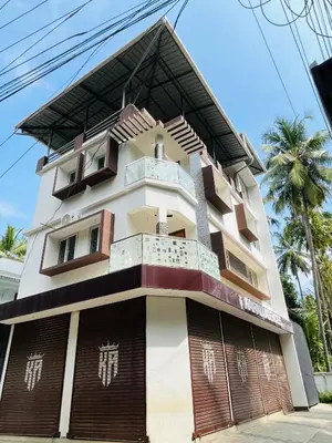 a building in front of a palm tree at Panakkal Tower in Guruvāyūr