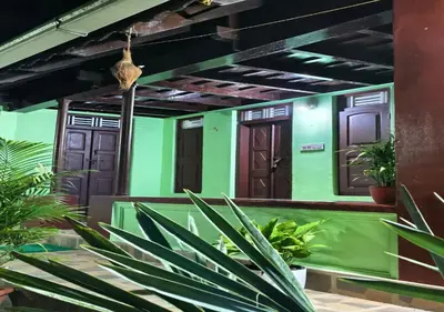 a house with green and brown doors and plants at Kuruva Heritage Home in Wayanad