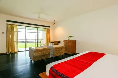 a bedroom with a bed and a living room with a window at Rainforest Resort in Athirappilly
