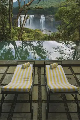 two chairs sitting in front of a view of a waterfall at Rainforest Resort in Athirappilly