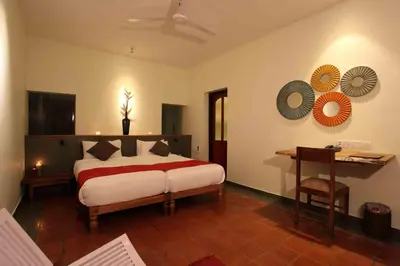 a bedroom with a bed and a desk in it at Rainforest Resort in Athirappilly