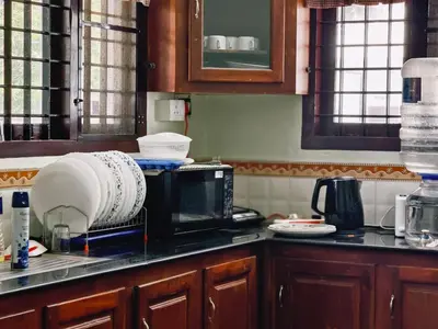 a kitchen with a drying rack on top of a microwave at Ambadis Beach View 3BHK Pool Villa in Pallipuram