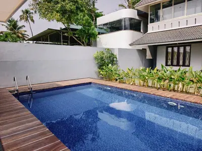 a swimming pool in front of a house at Ambadis Beach View 3BHK Pool Villa in Pallipuram