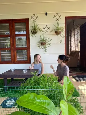 two women sitting at a table in a garden at Merchants Tranquility Home in Vythiri