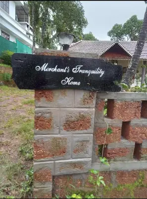 a sign on a brick wall with a yard at Merchants Tranquility Home in Vythiri