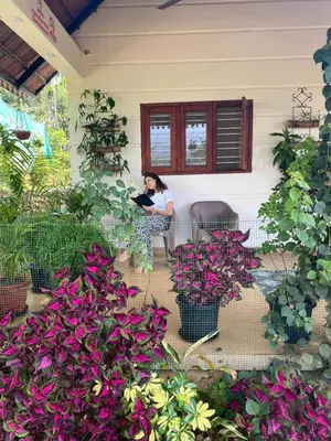 a woman sitting in a chair on a porch with flowers at Merchants Tranquility Home in Vythiri