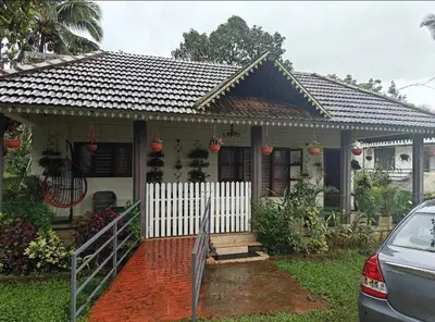 a small house with a white fence in front of it at Merchants Tranquility Home in Vythiri