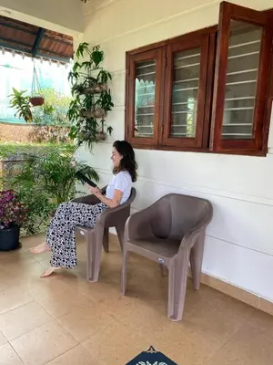 a woman sitting in a chair on a porch at Merchants Tranquility Home in Vythiri