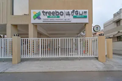 a white fence in front of a building with a sign at Treebo Premium Cachet Suites in Coimbatore